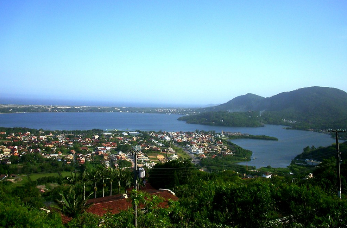 Vista do alto da Lagoa da Conceição em Florianópolis, com paisagem que abrange a lagoa, morros e casas à beira da água